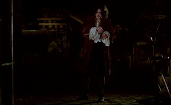 Movie still from “Heart of Glass” (1976), directed by Werner Herzog – A woman in a red coat standing in a dark room; Wide shot, Low angle