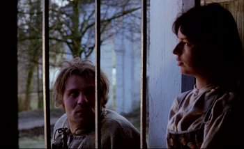 Movie still from “Heart of Glass” (1976), directed by Werner Herzog – A man and a woman standing next to each other in front of a building; Medium shot, Low angle