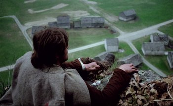 Movie still from “Heart of Glass” (1976), directed by Werner Herzog – A man standing on top of a building looking down; Wide shot, High angle