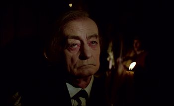 Movie still from “Heart of Glass” (1976), directed by Werner Herzog – An older man in a suit and tie looking sad; Close Up shot, Over the shoulder angle