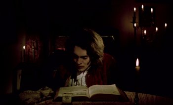 Movie still from “Heart of Glass” (1976), directed by Werner Herzog – A man sitting at a table reading a book; Medium shot, High angle