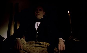 Movie still from “Heart of Glass” (1976), directed by Werner Herzog – An old man sitting in a chair with a candle in the background; Medium shot, High angle