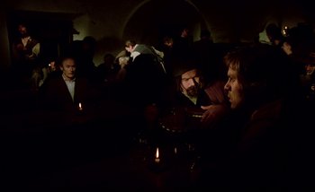 Movie still from “Heart of Glass” (1976), directed by Werner Herzog – A group of people sitting around a table with candles; Medium shot, Over the shoulder angle