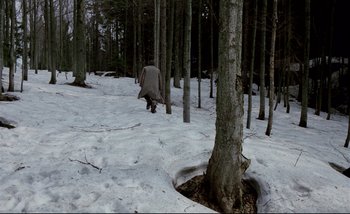 Movie still from “Heart of Glass” (1976), directed by Werner Herzog – A person walking in the snow near a tree; Extreme Wide shot, High angle