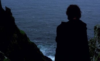 Movie still from “Heart of Glass” (1976), directed by Werner Herzog – A man standing on a cliff looking out at the ocean; Wide shot, Low angle