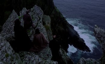 Movie still from “Heart of Glass” (1976), directed by Werner Herzog – Two men sitting on a cliff looking out at the ocean; Extreme Wide shot, High angle