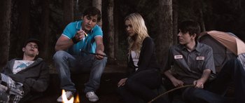 Movie still from “Tucker and Dale vs Evil” (2010), directed by Eli Craig – A man and a woman sitting next to each other near a fire; Medium shot, Over the shoulder angle