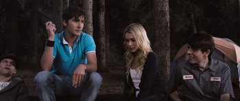 Movie still from “Tucker and Dale vs Evil” (2010), directed by Eli Craig – A man and a woman sitting on the ground in the woods; Medium shot, Over the shoulder angle