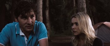 Movie still from “Tucker and Dale vs Evil” (2010), directed by Eli Craig – A man and a woman sitting next to each other in front of trees; Medium shot, Over the shoulder angle