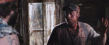 Movie still from “Tucker and Dale vs Evil” (2010), directed by Eli Craig – A man in a brown shirt wearing a hat and holding a stick; Close Up shot, Over the shoulder angle