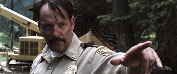 Movie still from “Tucker and Dale vs Evil” (2010), directed by Eli Craig – A man in a police uniform pointing to the camera; Close Up shot, Over the shoulder angle