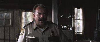 Movie still from “Tucker and Dale vs Evil” (2010), directed by Eli Craig – A man in a police uniform is looking at the camera; Close Up shot, Low angle
