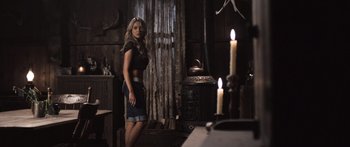 Movie still from “Tucker and Dale vs Evil” (2010), directed by Eli Craig – A woman standing next to candles in a room; Wide shot, Low angle