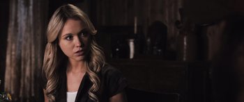 Movie still from “Tucker and Dale vs Evil” (2010), directed by Eli Craig – A beautiful blonde woman sitting in front of a dark background; Close Up shot, Over the shoulder angle