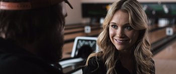Movie still from “Tucker and Dale vs Evil” (2010), directed by Eli Craig – A beautiful young lady smiling at the camera while sitting in front of a laptop computer; Close Up shot, Over the shoulder angle