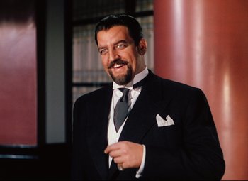 Movie still from “Heaven Can Wait” (1943), directed by Ernst Lubitsch – A man in a suit and tie smiling for the camera; Medium shot, Over the shoulder angle