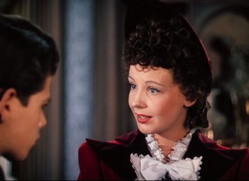 Movie still from “Heaven Can Wait” (1943), directed by Ernst Lubitsch – A woman in a red dress and a white hat; Close Up shot, Over the shoulder angle
