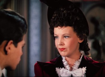 Movie still from “Heaven Can Wait” (1943), directed by Ernst Lubitsch – A woman in a black hat and a red jacket; Close Up shot, Over the shoulder angle