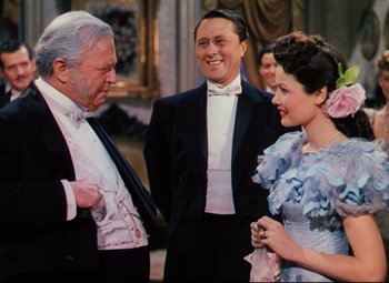 Movie still from “Heaven Can Wait” (1943), directed by Ernst Lubitsch – A group of people in formal wear standing next to each other; Medium shot, Over the shoulder angle