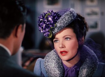 Movie still from “Heaven Can Wait” (1943), directed by Ernst Lubitsch – A woman wearing a purple hat with a purple flower on top of her head; Close Up shot, Over the shoulder angle