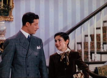 Movie still from “Heaven Can Wait” (1943), directed by Ernst Lubitsch – A man and a woman standing next to each other in front of a staircase; Medium shot, Over the shoulder angle