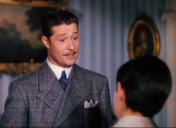 Movie still from “Heaven Can Wait” (1943), directed by Ernst Lubitsch – A man in a suit talking to a young boy; Medium shot, Over the shoulder angle