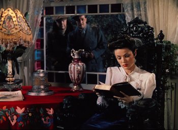 Movie still from “Heaven Can Wait” (1943), directed by Ernst Lubitsch – A woman sitting in a chair reading a book; Medium shot, High angle