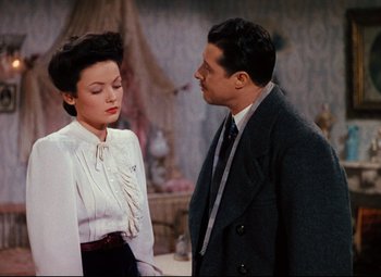 Movie still from “Heaven Can Wait” (1943), directed by Ernst Lubitsch – A man and a woman standing next to each other in a room; Medium shot, Over the shoulder angle