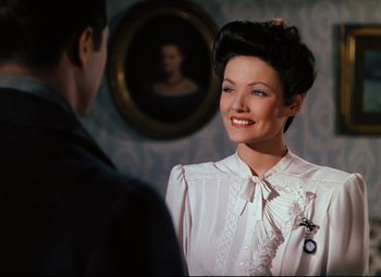 Movie still from “Heaven Can Wait” (1943), directed by Ernst Lubitsch – A woman in a white dress smiling at a man in a black suit; Medium shot, Over the shoulder angle
