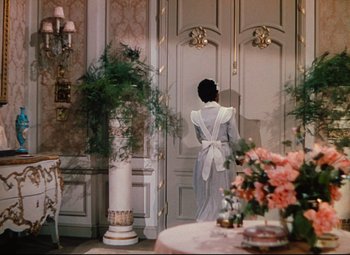 Movie still from “Heaven Can Wait” (1943), directed by Ernst Lubitsch – A woman standing in front of a door in a room; Wide shot, Over the shoulder angle