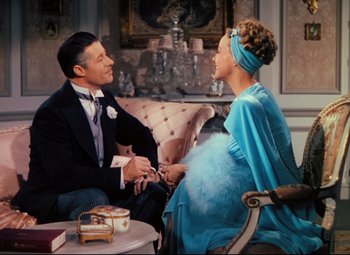 Movie still from “Heaven Can Wait” (1943), directed by Ernst Lubitsch – A man and a woman sitting on a couch talking to each other; Medium shot, High angle