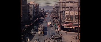 An old photo of a busy city street with cars and buses