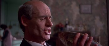 Movie still from “Heavenly Creatures” (1994), directed by Peter Jackson – A man with a bald head holding a fish in his hand; Close Up shot, Low angle