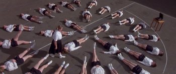 Movie still from “Heavenly Creatures” (1994), directed by Peter Jackson – A group of people laying on the ground with their feet on the ground; Extreme Wide shot, High angle