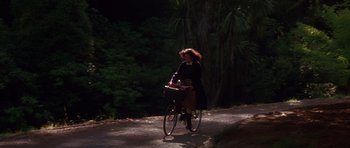 Movie still from “Heavenly Creatures” (1994), directed by Peter Jackson – A woman riding a bike down a dirt road; Wide shot, High angle