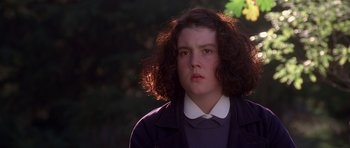 Movie still from “Heavenly Creatures” (1994), directed by Peter Jackson – A young woman with a curly hair looks at the camera; Close Up shot, Low angle