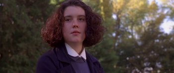 Movie still from “Heavenly Creatures” (1994), directed by Peter Jackson – A young woman with curly brown hair wearing a jacket and tie; Close Up shot, Low angle