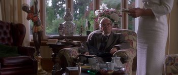 Movie still from “Heavenly Creatures” (1994), directed by Peter Jackson – An older man sitting in a chair in front of a tea set; Medium shot, Low angle