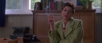 Movie still from “Heavenly Creatures” (1994), directed by Peter Jackson – A woman smoking a cigarette while sitting at a table; Medium shot, Over the shoulder angle