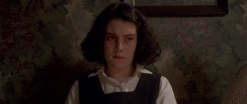 Movie still from “Heavenly Creatures” (1994), directed by Peter Jackson – A young woman with long black hair wearing a white shirt and black vest; Close Up shot, High angle