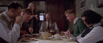 Movie still from “Heavenly Creatures” (1994), directed by Peter Jackson – A group of people sitting around a table eating food; Medium shot, Over the shoulder angle