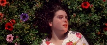 Movie still from “Heavenly Creatures” (1994), directed by Peter Jackson – A woman laying in the grass with her eyes closed; Close Up shot, Overhead angle