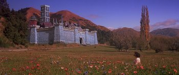 Movie still from “Heavenly Creatures” (1994), directed by Peter Jackson – A blue castle with flowers in front of it; Extreme Wide shot, Low angle