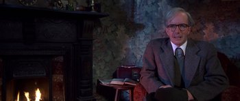Movie still from “Heavenly Creatures” (1994), directed by Peter Jackson – An older man sitting at a table in front of a fireplace; Medium shot, Low angle