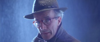 Movie still from “Heavenly Creatures” (1994), directed by Peter Jackson – An older man wearing glasses and a hat; Close Up shot, Low angle