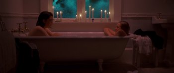 Movie still from “Heavenly Creatures” (1994), directed by Peter Jackson – Two women are in a bath tub with candles in the background; Wide shot, High angle
