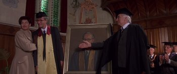 Movie still from “Heavenly Creatures” (1994), directed by Peter Jackson – A man in a graduation cap and gown holding a painting; Medium shot, Low angle