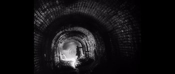 Movie still from “Heavenly Creatures” (1994), directed by Peter Jackson – A man standing inside of an old brick tunnel; Wide shot, Low angle