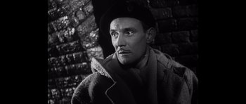 Movie still from “Heavenly Creatures” (1994), directed by Peter Jackson – A man wearing a coat and hat in a black and white photo; Close Up shot, Low angle