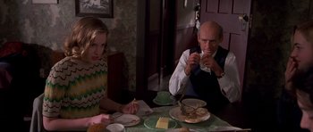 Movie still from “Heavenly Creatures” (1994), directed by Peter Jackson – Two people sitting at a dinner table with food; Medium shot, Over the shoulder angle